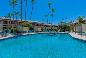 a large swimming pool in front of a hotel with palm trees at La Fuente Inn & Suites in Yuma