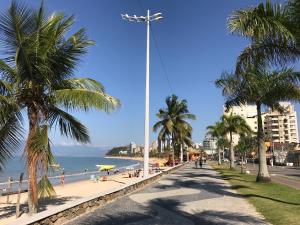a beach with palm trees and people on the beach at Farol das Gaivotas Pousada e Residence in Caraguatatuba