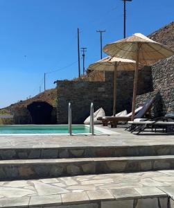 a pool with an umbrella and chairs and a slide at Villa de Estrella in Agios Dimitrios