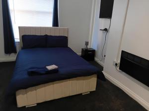 a bed with a blue blanket and a book on it at Studio Sleeps 2 with Parking in Oldbury