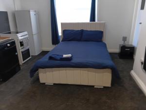a bedroom with a bed with a blue blanket at Studio Sleeps 2 with Parking in Oldbury
