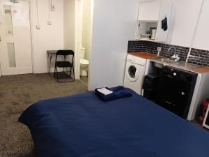 a small room with a bed and a washing machine at Studio Sleeps 2 with Parking in Oldbury +2 photos