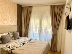 a bedroom with a bed and a large window at apartment Danijela in Radanovići