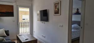 a living room with a couch and a television on the wall at Espectaculares Aptos Castillo de Bellver in Camas