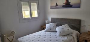 a bedroom with a bed with white sheets and a window at Espectaculares Aptos Castillo de Bellver in Camas