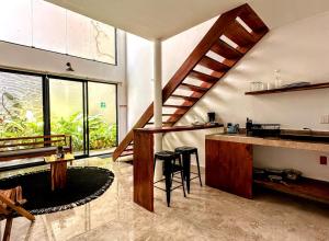 a room with a staircase and a kitchen with stools at Yaakun in Bacalar