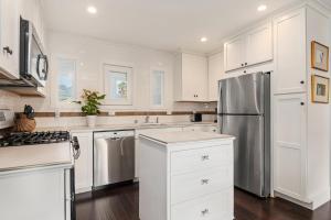 a kitchen with white cabinets and a stainless steel refrigerator at California Comfort in Santa Barbara