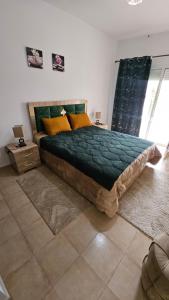 a bedroom with a bed with a green comforter and yellow pillows at Villa lux AP2 in Saïdia +16 photos