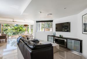 uma sala de estar com um sofá de couro preto e uma televisão em Park Cove Apartment 1, Little Cove em Noosa Heads