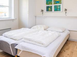 a white bed with white sheets and pillows on it at Hals Apartment 100m from Beach in Hals
