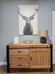 a wooden dresser with a deer picture on the wall at Chalet les Marmottons in Cauterets