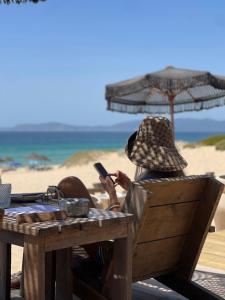 a person sitting at a table at the beach with a cell phone at Pousada Mar de Calma in Montemor-o-Novo