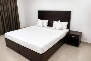 a bedroom with a large bed with white sheets and pillows at Hotel Rastro Palace in New Delhi