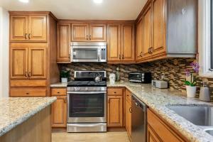 a kitchen with wooden cabinets and stainless steel appliances at Garden Escape in Santa Barbara +12 photos