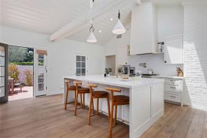 a kitchen with white cabinets and a large island with bar stools at Hedgerow Jewel Box in Santa Barbara +38 photos
