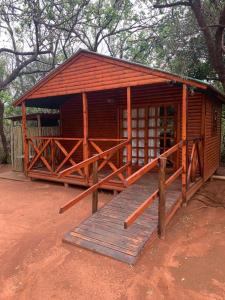 a small wooden cabin with a wooden ramp in front at Mountain Sanctuary Park in Rustenburg