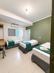 a room with three beds and a desk in it at Emburi Hotel in Piratininga