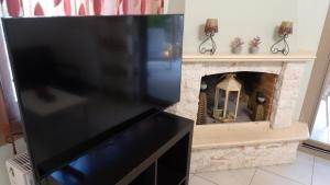 a flat screen tv sitting next to a fireplace at Isidoros House in Keramoti