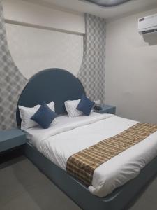 a bedroom with a large bed with a blue headboard at Hotel Rudrax in Waghoria