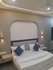 a bedroom with a bed with blue and white pillows at Hotel Rudrax in Waghoria