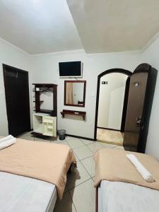 a room with two beds and a mirror and a tv at Hotel Akuto's in Aparecida