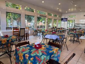 a dining room with tables and chairs and windows at Emburi Hotel in Piratininga