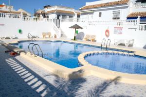 a pool at a resort with chairs and tables at Super Cute Camposol 2 bed with Community Pool in Mazarrón