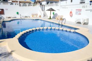 a pool at a resort with chairs and tables at Super Cute Camposol 2 bed with Community Pool in Mazarrón