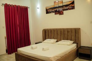 a bedroom with a bed with red curtains at US Apartment in Nochchiyagama