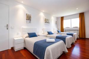 three beds in a room with white walls and wood floors at Magnifica Planet Costa Dorada in Cambrils