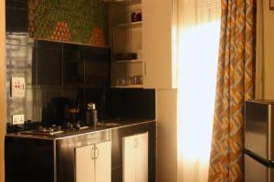 a kitchen with black and white cabinets and a refrigerator at Gejja Cottage in Lwanga