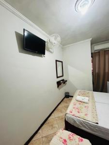 a room with two beds and a flat screen tv at Hotel Akuto's in Aparecida