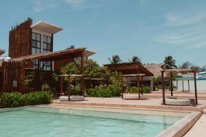 a swimming pool with umbrellas and a building at Totem Beach Club - Celestun in Celestún