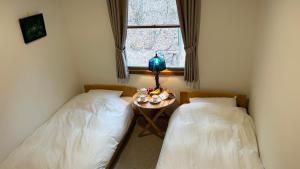 two beds in a room with a table and a window at Guesthouse Lavande in Chino
