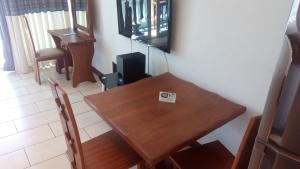 a dining room with a wooden table and a television at Bamburi Beach Studio Apartment B41 in Bamburi