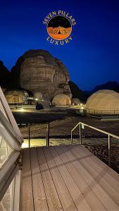 a wooden deck with a view of a mountain at night at SEVEN PILLARS lUXURY CAMP in Wadi Rum