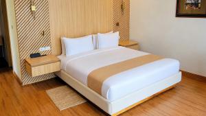 a bedroom with a large white bed with wooden floors at Denbi Eco Lodge in Greater Aman