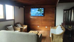 ein Wohnzimmer mit Stühlen und einem Fernseher an der Wand in der Unterkunft Maderobeach1 in Máncora