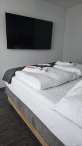Eine Reihe weißer Betten und ein Fernseher an der Wand in der Unterkunft Relax Corner in Einigen
