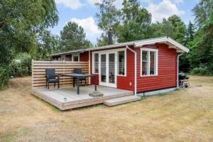 a red cabin with a table and chairs on a deck at 5020-Askeby-Faergensvaenge-18 in Askeby