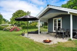 a patio with an umbrella and a fire pit at fj1203-Jaegerspris-Birkagervej-14 in Jægerspris
