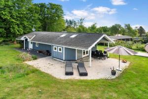 a blue house with a patio and an umbrella at fj1203-Jaegerspris-Birkagervej-14 in Jægerspris +11 photos