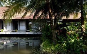 a house with a pond and a palm tree at Haven Nest Retreat in Ấp Phú Hòa (3)