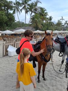 a man and a girl standing next to a horse on the beach at Hostal La Bendición Buritaca in Santa Marta