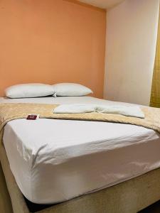 a bedroom with two beds with white sheets and pillows at Hostal La Bendición Buritaca in Santa Marta