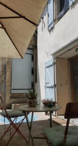 a patio with a table and chairs in front of a building at Aux Mimosas in La Tour-sur-Orb