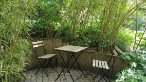 two chairs and a wooden table in a garden at Le Clos de Saussac in Yssingeaux