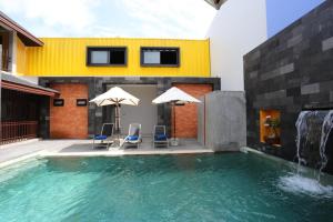 a swimming pool with two chairs and a waterfall at Guan Yu Boutique Hotel in Ban Thong Yi