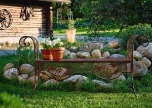 a bench sitting in the grass with flowers on it at Majatalo Puukarin Pysäkki in Nurmes