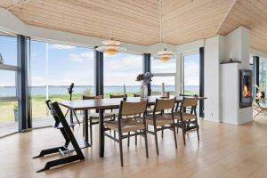a dining room with a table and chairs and windows at LF15163-Hojslev-Jelsevej-163 in Lundø